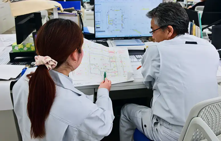 真剣な視線で、設計図を検討する二人の姿。