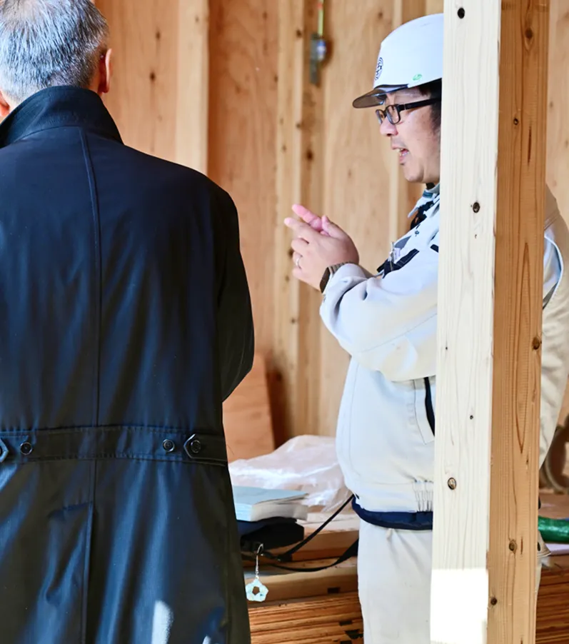 建物の建設現場で、熟練の職人さんと建築士が話し合っています